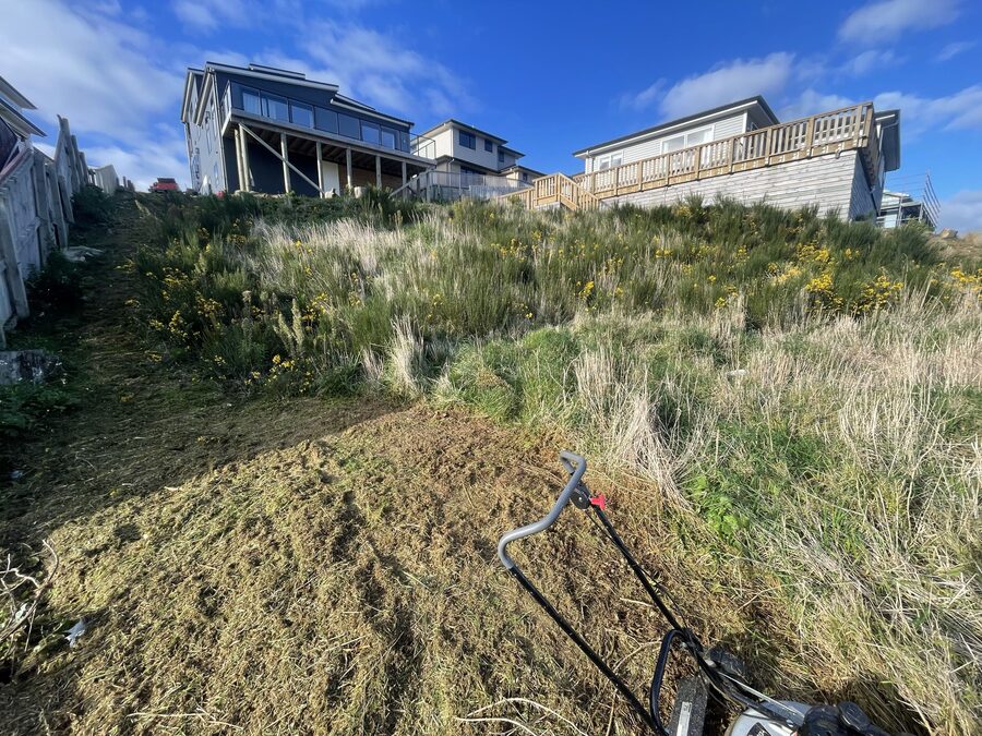 Mowing a steep hillside with houses above